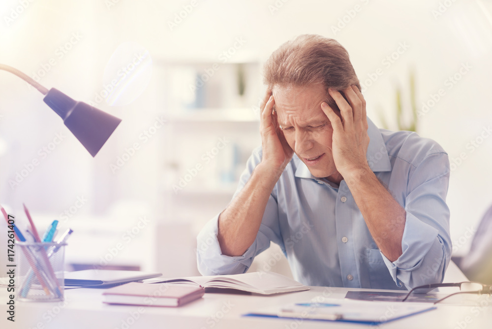 Depressed male office worker having a headache Depressed male office worker having a headache