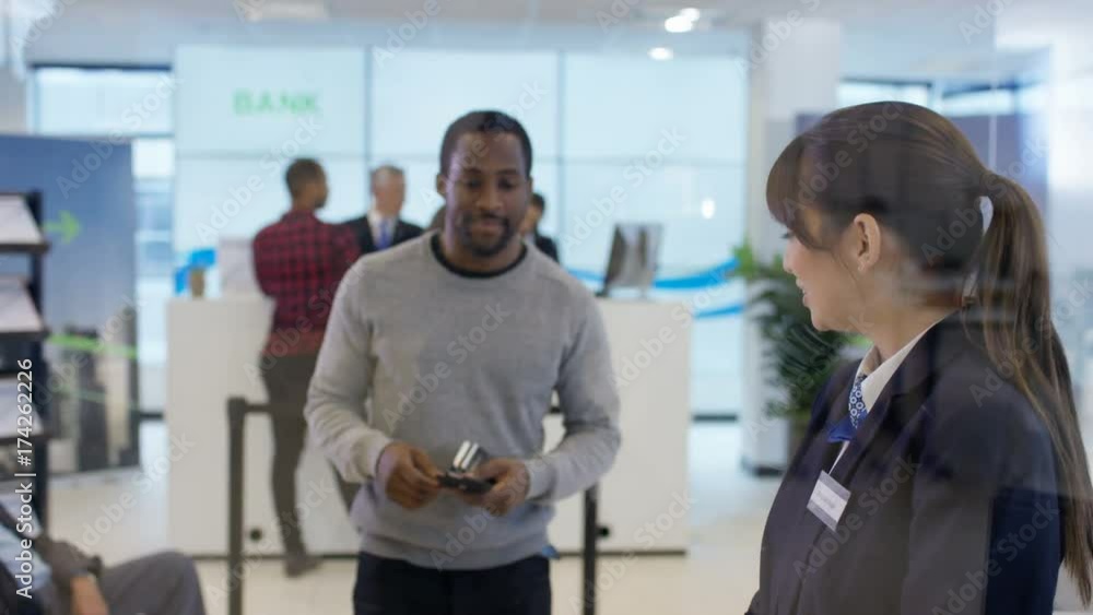 Worker in modern bank helps customer to use interactive atm machine Worker in modern bank helps customer to use interactive atm machine