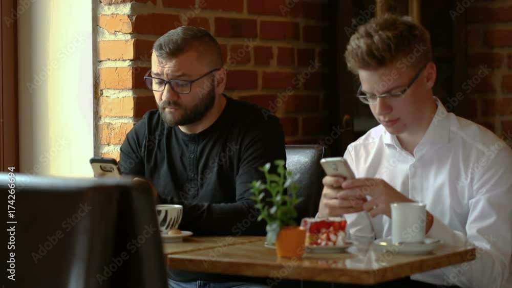 Businessmen sitting in the cafe and texting on smartphones
Businessmen sitting in the cafe and texting on smartphones