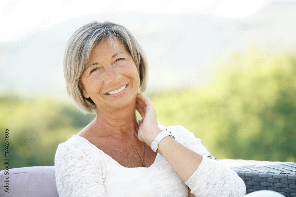Portrait of cheerful senior woman relaxing in outdoors sofa Portrait of cheerful senior woman relaxing in outdoors sofa
