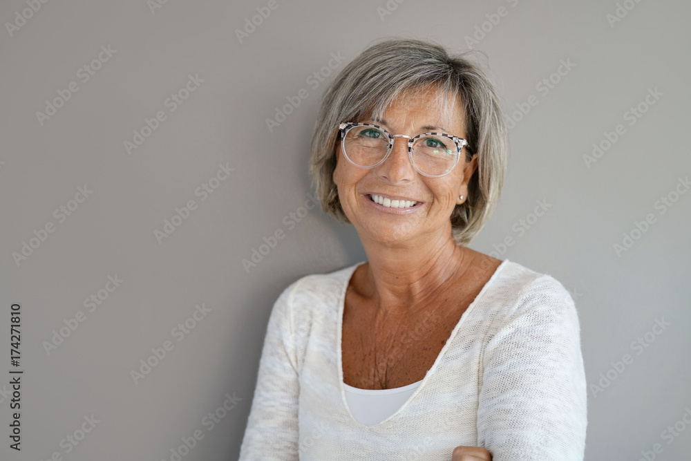 Portrait of mature woman with eyeglasses on grey background Portrait of mature woman with eyeglasses on grey background