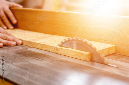 Carpenter cutting wooden board with circular saw.
