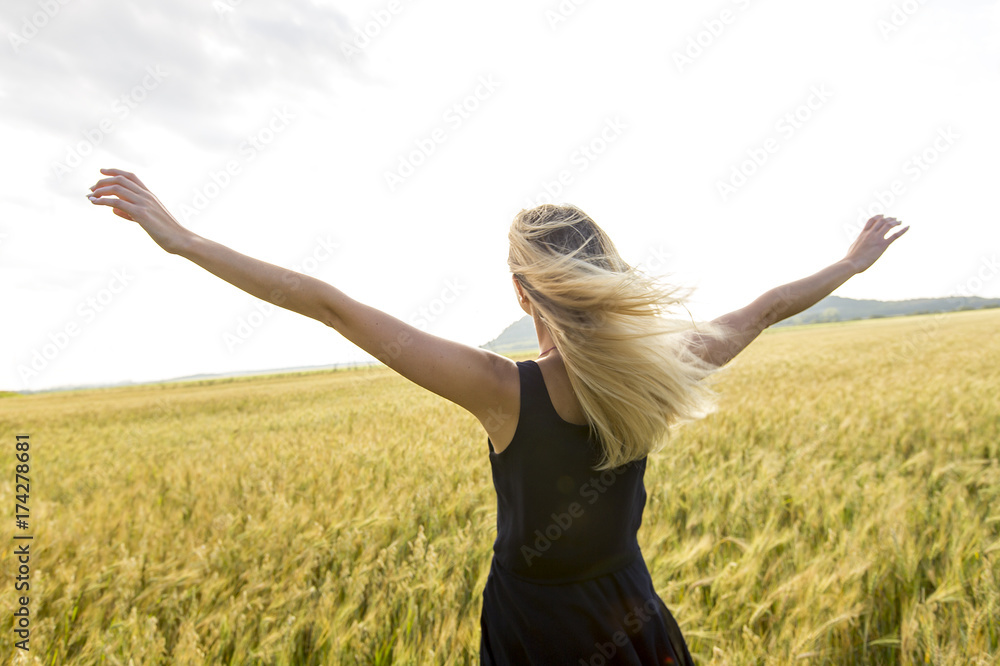 Fototapeta premium Happy, satisfied young woman standing in the wheat field.