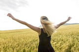 Happy, satisfied young woman standing in the wheat field.