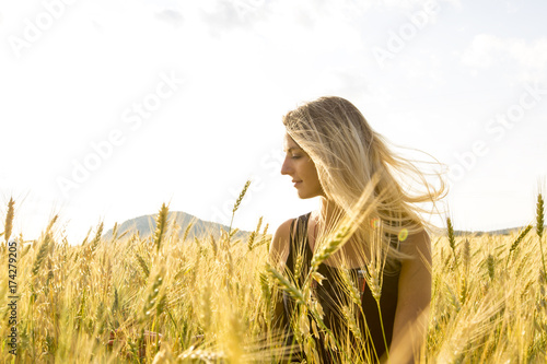 Happy, satisfied young woman standing in the wheat field. photo