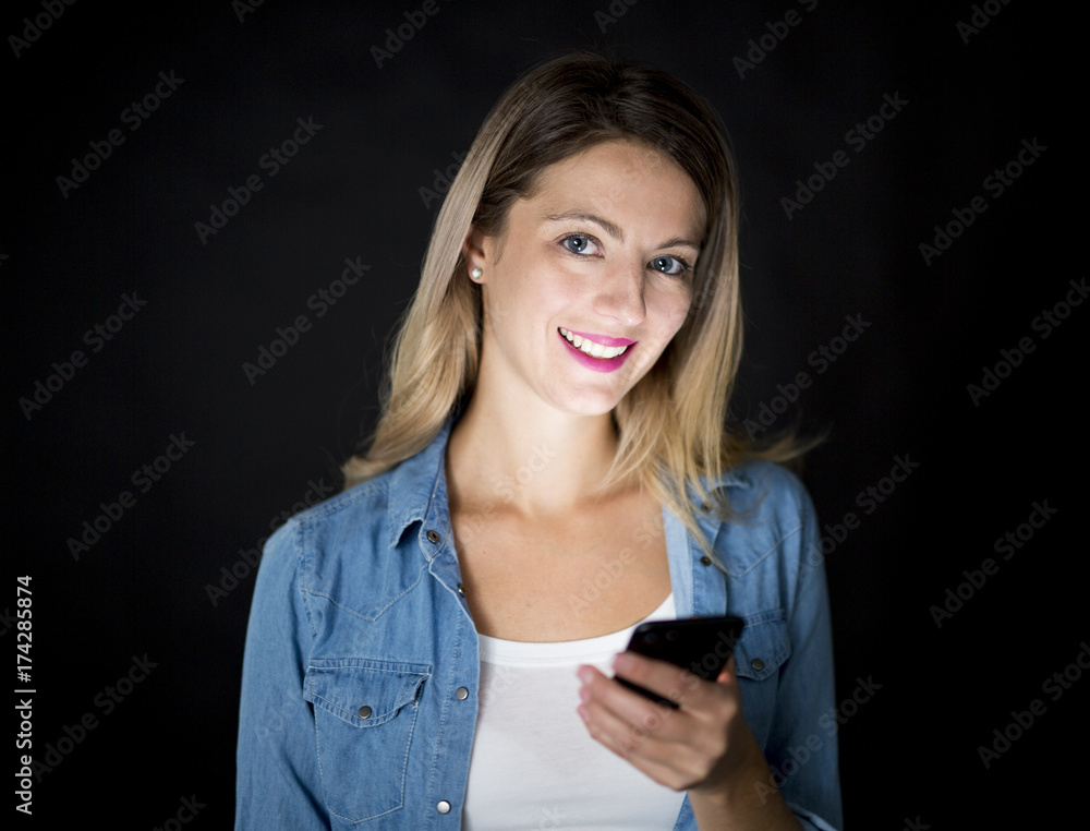 Closeup of woman holding and using modern smart phone on black background Closeup of woman holding and using modern smart phone on black background