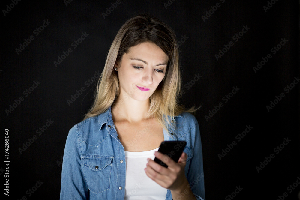 Closeup of woman holding and using modern smart phone on black background Closeup of woman holding and using modern smart phone on black background