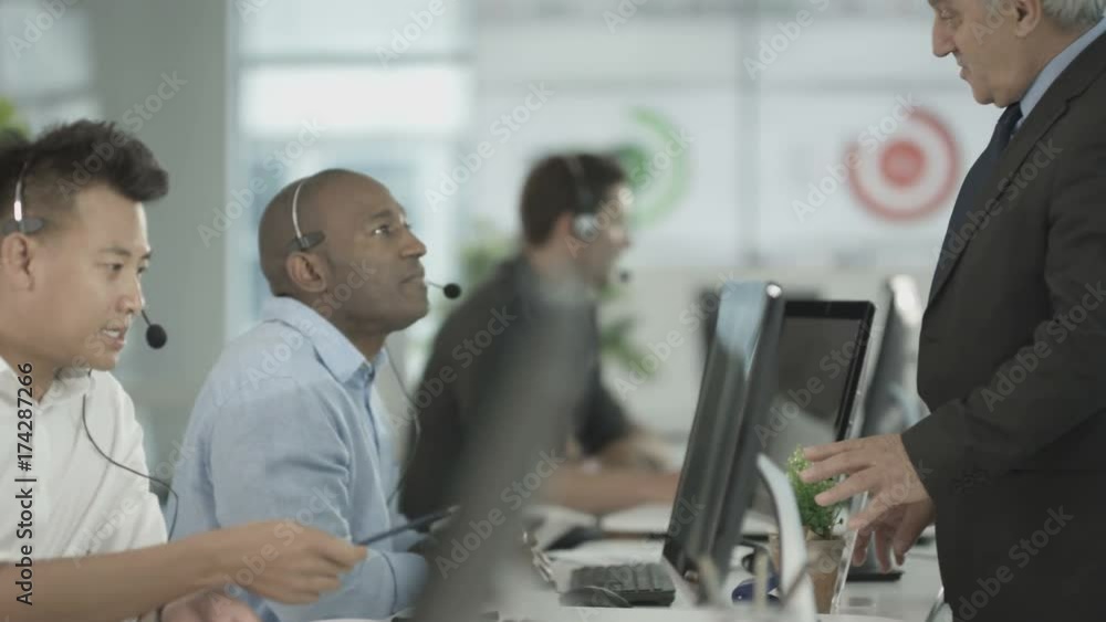  Customer service ops taking calls in busy call center with manager overseeing