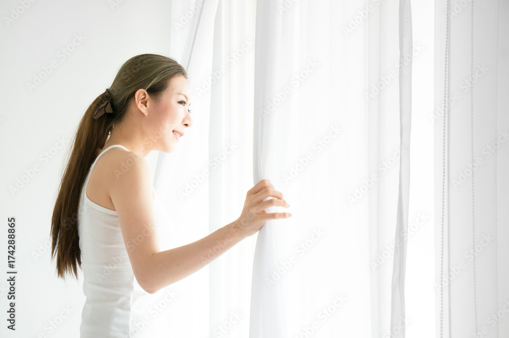 Asian beauty woman wake up and move white curtain on white bed in white bedroom in morning Asian beauty woman wake up and move white curtain on white bed in white bedroom in morning