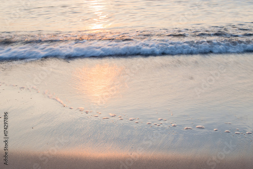 Sunset soft beautiful ocean wave on sandy beach. romantic travel background.
