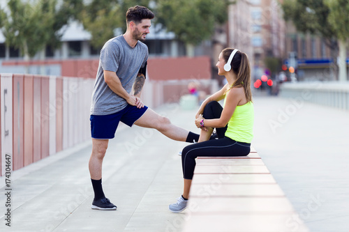 Beautiful young couple relaxing after running in the street.