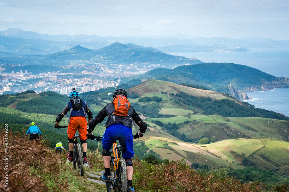 Naklejka premium Basque mountain bikers descending into the distance towards San Sebastian