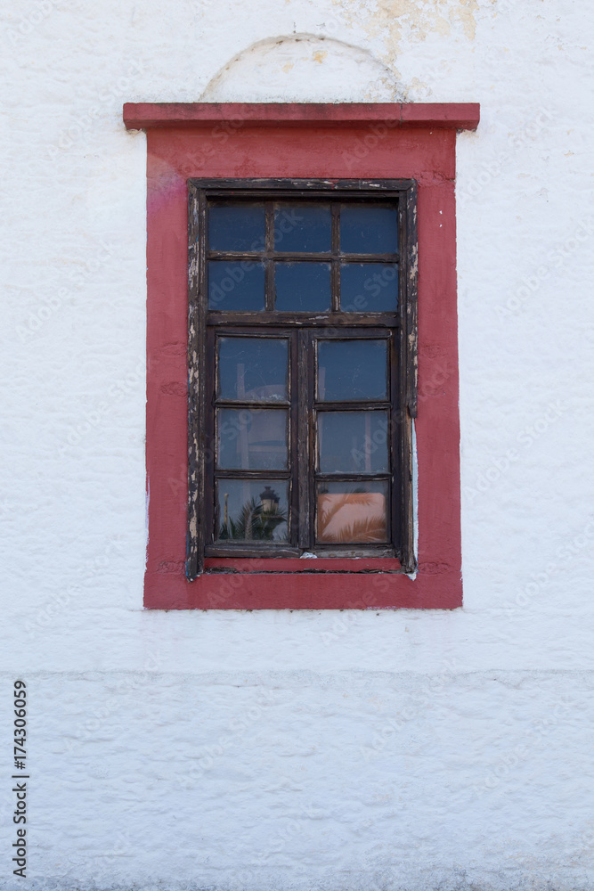 Old red window on a white wall, Greece.