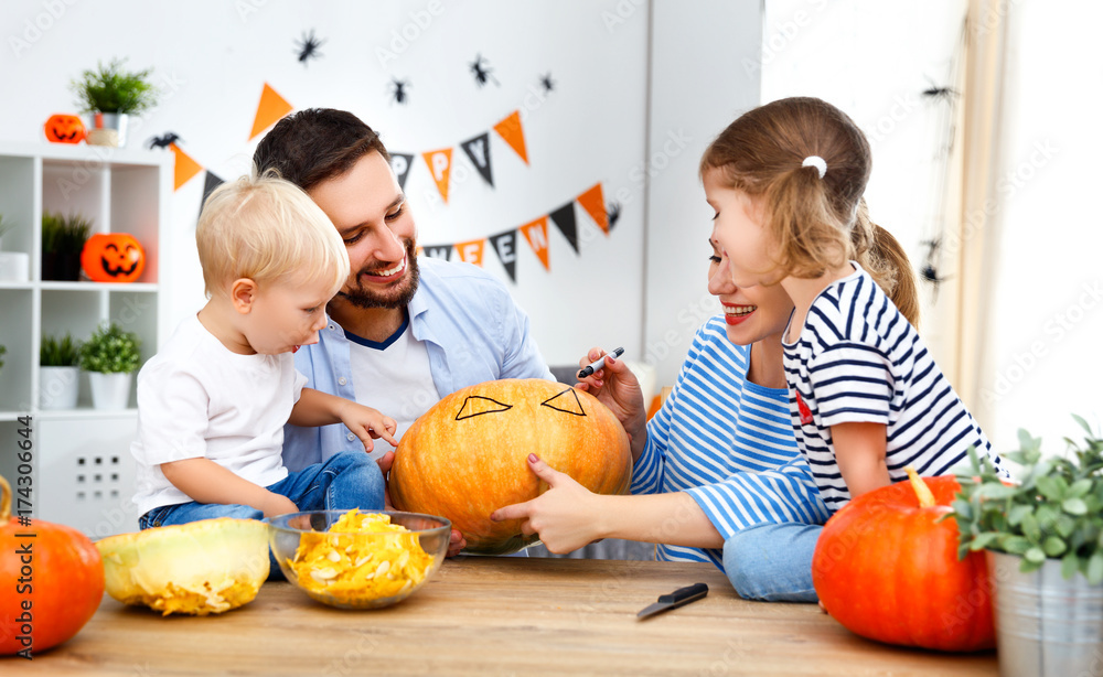 Fototapeta premium happy family mother father and children cut pumpkin for halloween