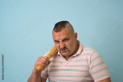 Young man with wooden baseball bat, on grey background.