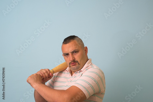 Young man with wooden baseball bat, on grey background.