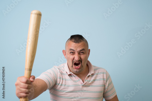 Young man with wooden baseball bat, on grey background.