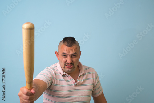 Young man with wooden baseball bat, on grey background.