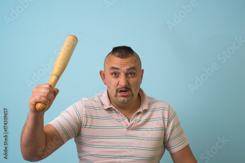 Young man with wooden baseball bat, on grey background.