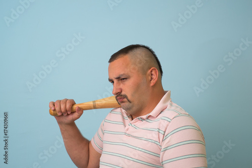 Young man with wooden baseball bat, on grey background.
