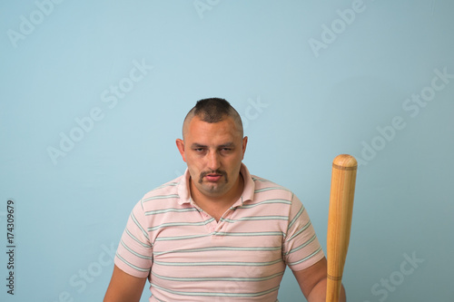 Young man with wooden baseball bat, on grey background.