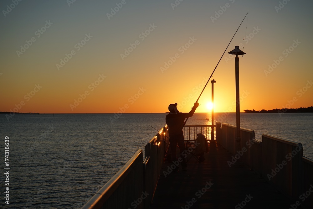 A man fishing on a Florida pier at sunset