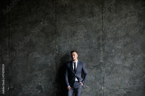 Handsome caucasian businessman dressed in the suit near the window in the loft interior studio