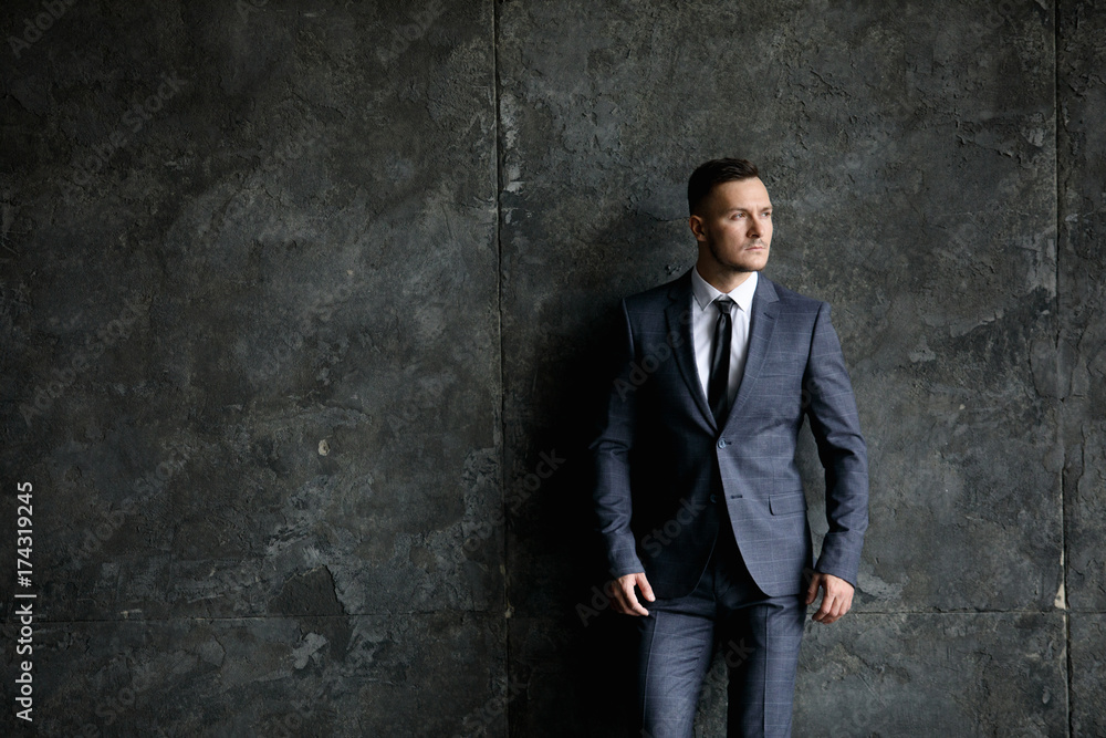 Portrait of stylish male dressed in a suit over grey background