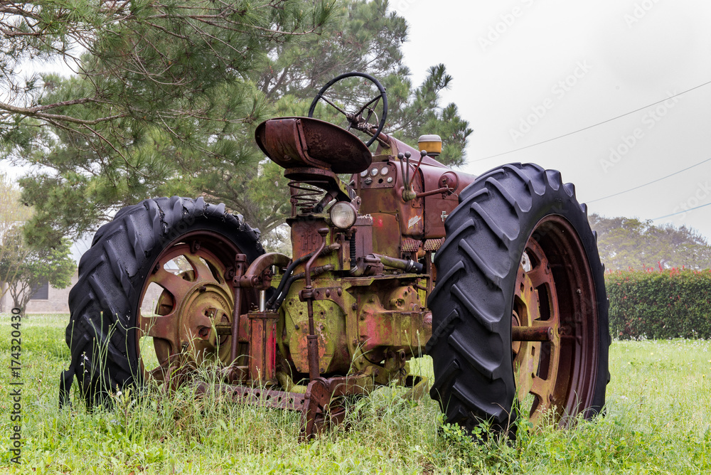 Obraz premium Old abandoned tractor sitting in the rain