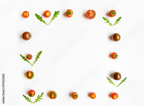 Fototapeta Naklejka Na Ścianę i Meble -  Cherry tomatoes and rocket salad leaves frame on white background. Flat lay