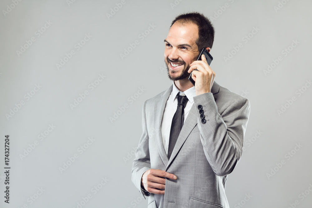 Business young man using his mobile phone over gray background. Business young man using his mobile phone over gray background.