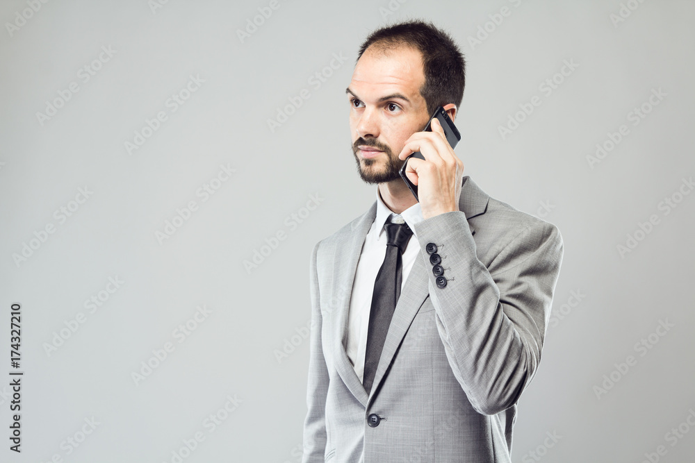 Business young man using his mobile phone over gray background. Business young man using his mobile phone over gray background.