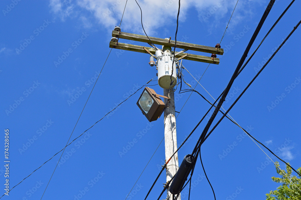 Telephone pole with lots of wires, cables, and a street light Telephone pole with lots of wires, cables, and a street light