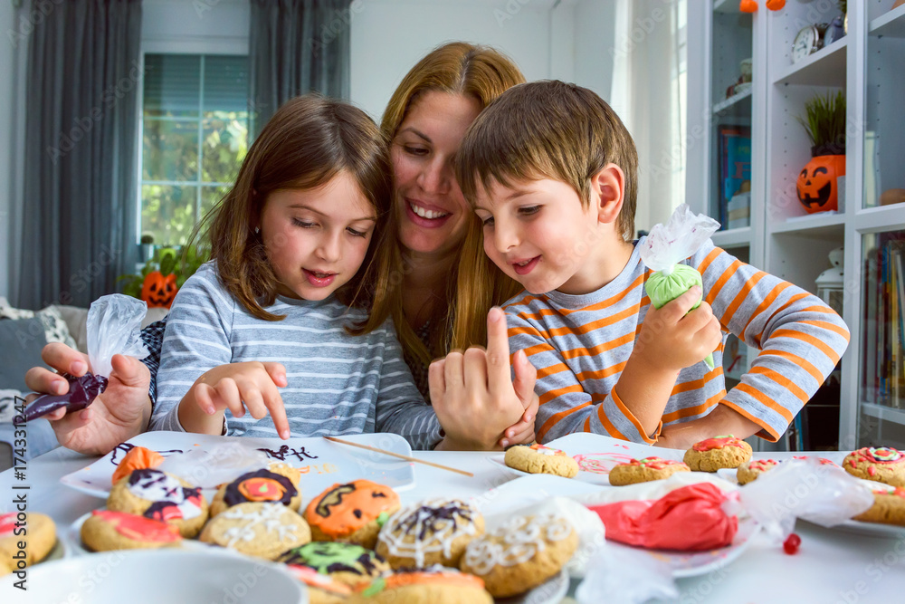 Mother with children decorating Halloween cookies Mother with children decorating Halloween cookies