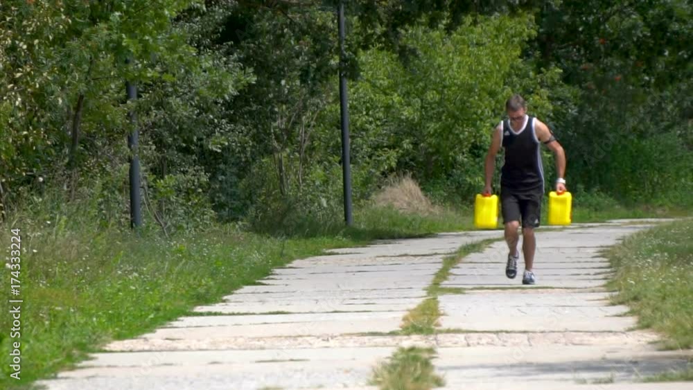 Man with yellow jerrycans runs down the road in the forest Man with yellow jerrycans runs down the road in the forest