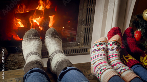 Family in wool socks celebrating Christmas at burning fireplace