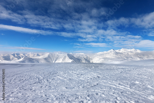 Ski slope, snow mountains and blue sky with clouds