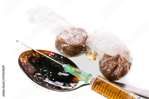 Fotografija Two wraps of brown drugs, probably heroin, with a dirty spoon and a prepared syr