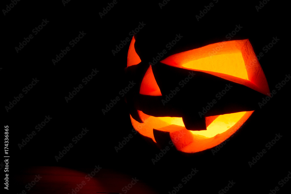 The concept of Halloween. The ghastly, ghastly pumpkin glows with a fiery yellow light. mystical jack lantern in the darkness, isolated on black The concept of Halloween. The ghastly, ghastly pumpkin glows with a fiery yellow light. mystical jack lantern in the darkness, isolated on black