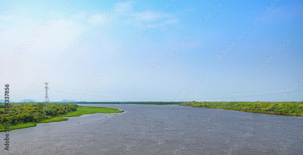Landscape of Paraguai river taken from the Ponte do Rio Paraguai bridge. The river, a blue sky day and the green vegetation on the margins of the river. Landscape of Paraguai river taken from the Ponte do Rio Paraguai bridge. The river, a blue sky day and the green vegetation on the margins of the river.