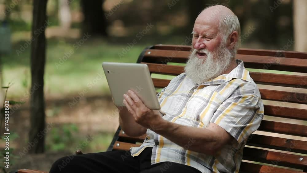 Attractive senior man using tablet on the bench Attractive senior man using tablet on the bench