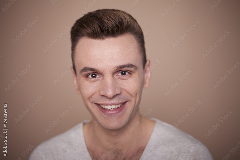 Portrait of a handsome smiling sexy young man in a white t-shirt near the grey background. Portrait of a handsome smiling sexy young man in a white t-shirt near the grey background.