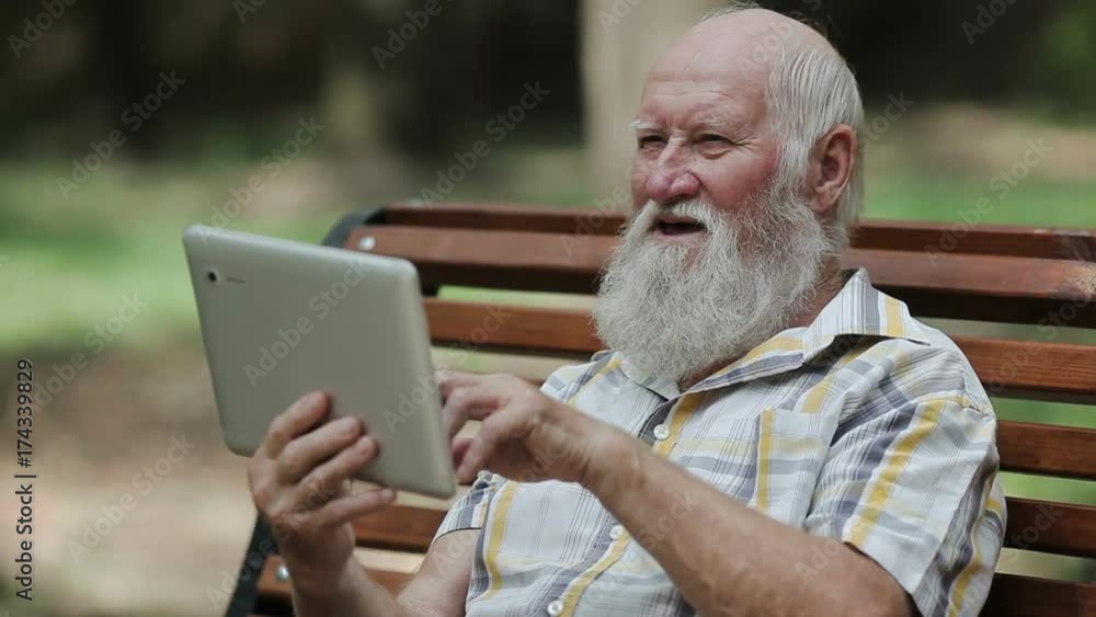 Attractive senior man using tablet on the bench