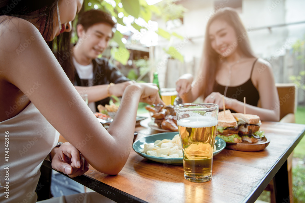 Beautiful Asian woman is having lunch with her friends. She has a smile and a laugh. beside her was a glass of beer placed on the table.