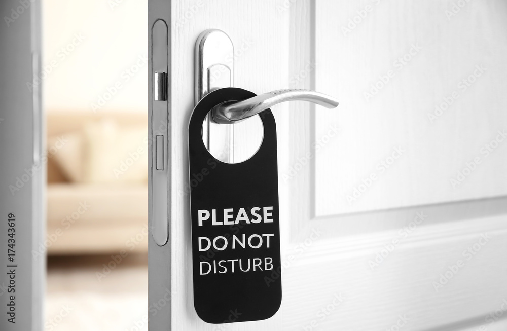 Fototapeta premium Open door with sign PLEASE DO NOT DISTURB on handle at hotel