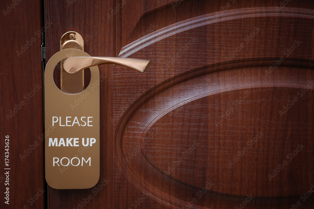 Naklejka premium Closed door with sign PLEASE MAKE UP ROOM on handle at hotel