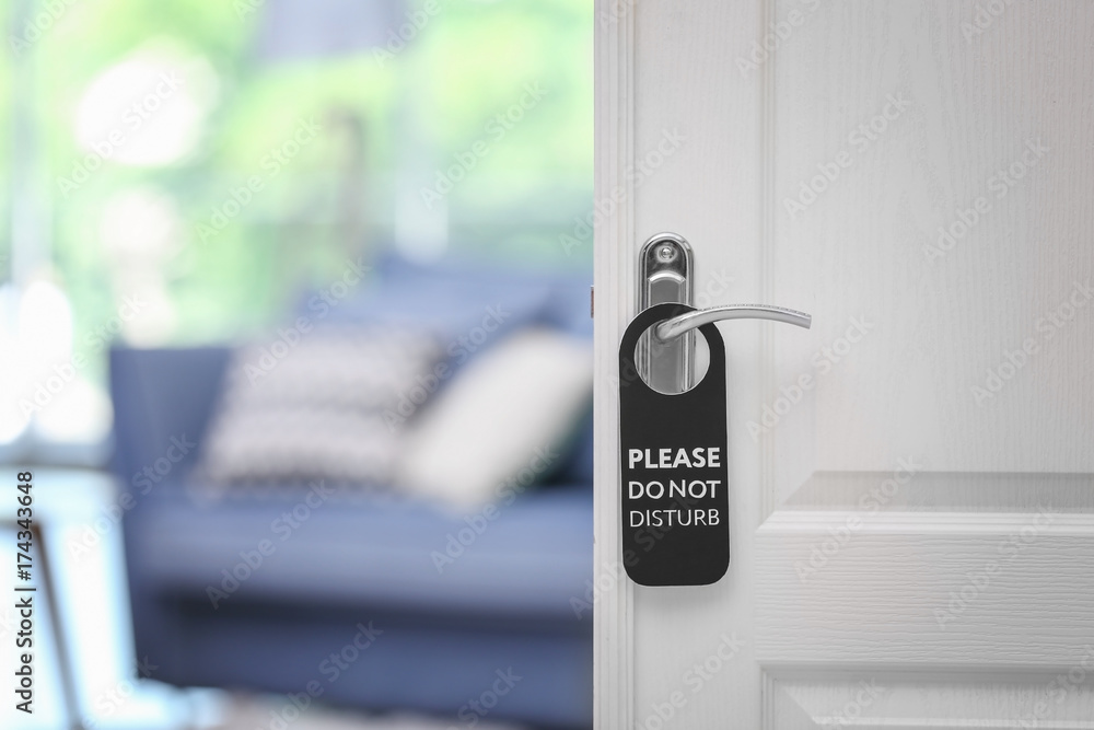 Naklejka premium Open door with sign PLEASE DO NOT DISTURB on handle at hotel