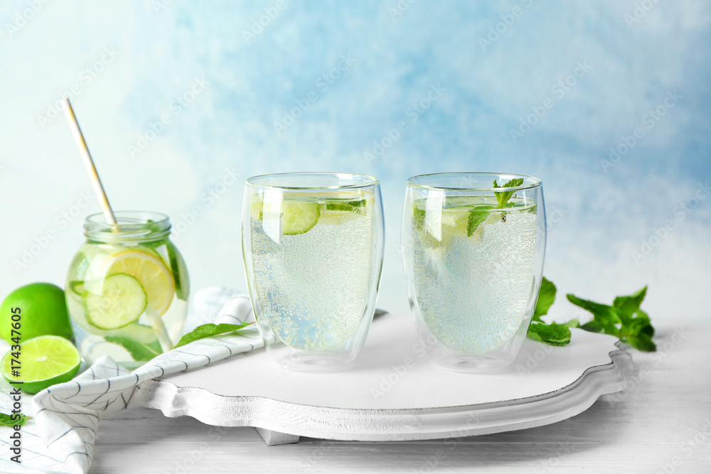 Delicious refreshing water with cucumber in glasses on wooden board Delicious refreshing water with cucumber in glasses on wooden board