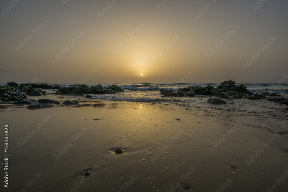 sunrise on a beach with waves and stones in the water