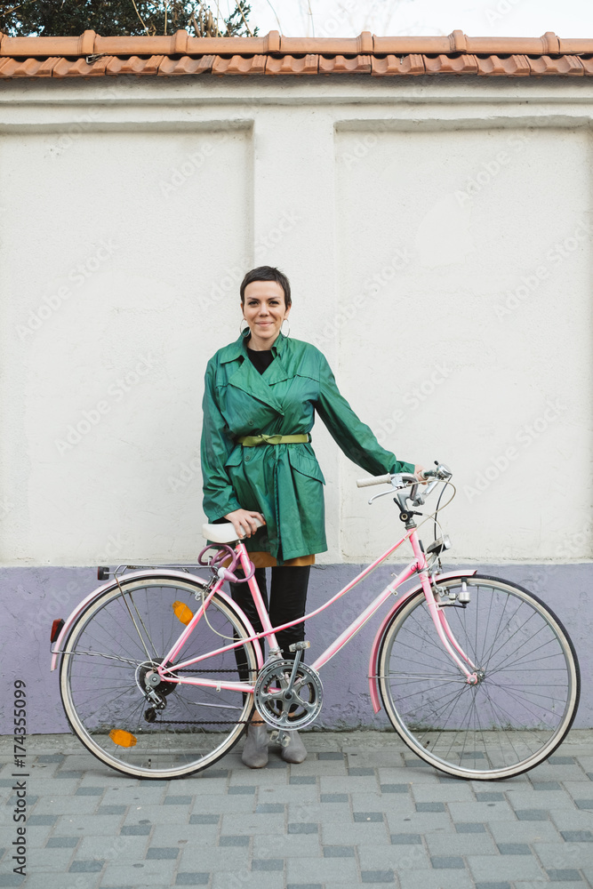 Woman with a Pink Bicycle Standing in front of the Purple Wall Woman with a Pink Bicycle Standing in front of the Purple Wall